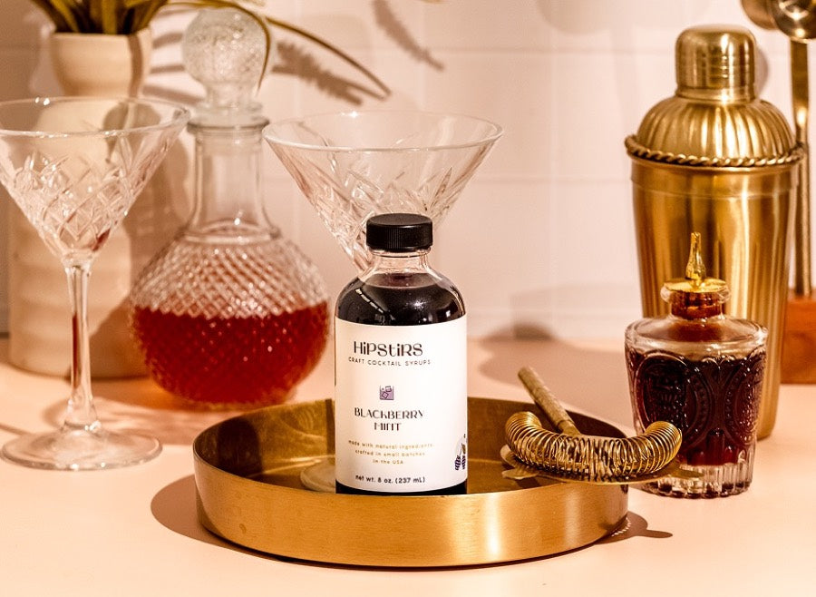 Blackberry Mint syrup on a brass tray with a decanter and shaker